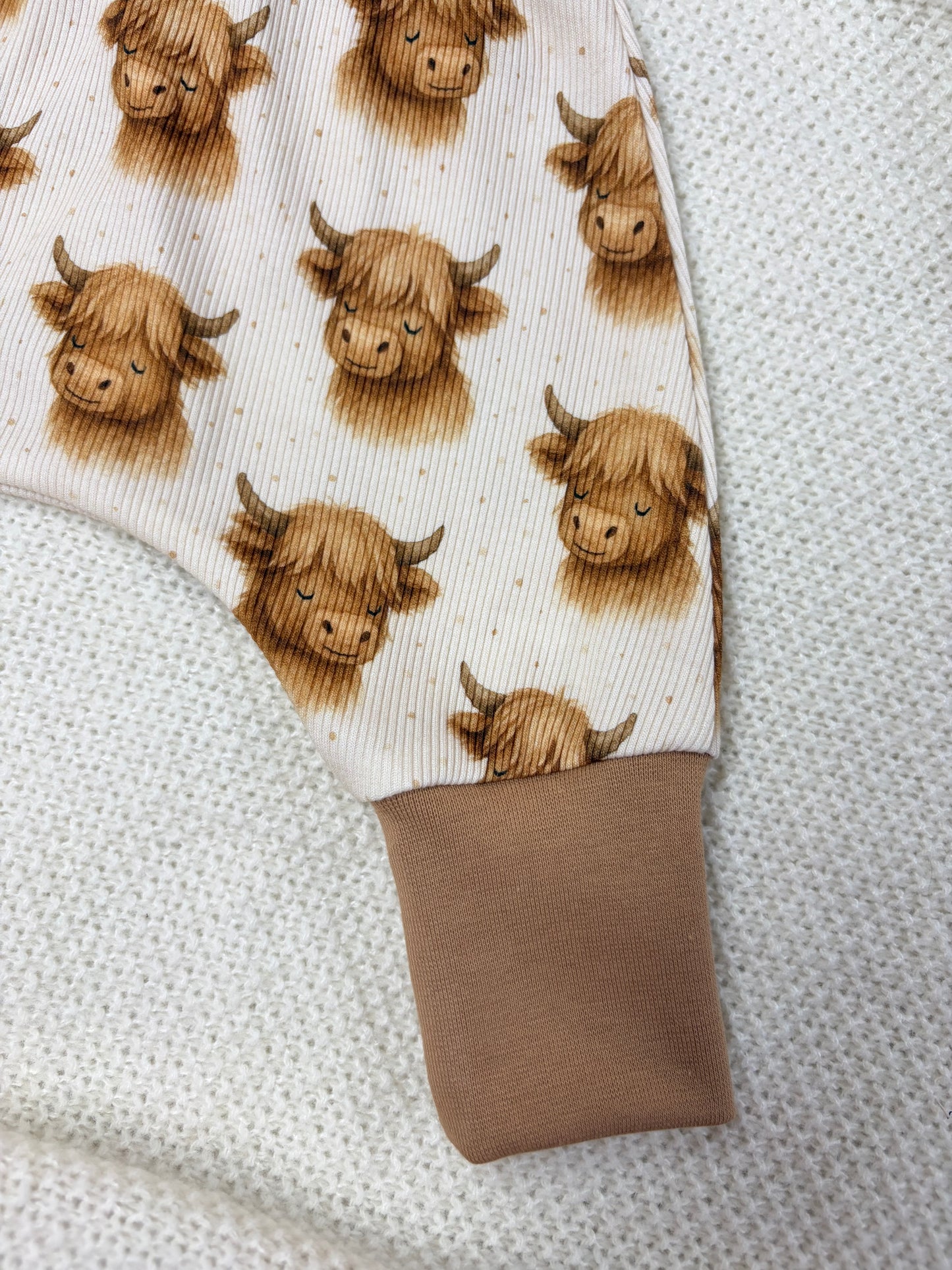 Nahansicht linkes Bein der handgemachten langen Pumphose aus Ripp-Jersey mit Hochlandrinder-Muster in Creme-Braun – OhMamaLina