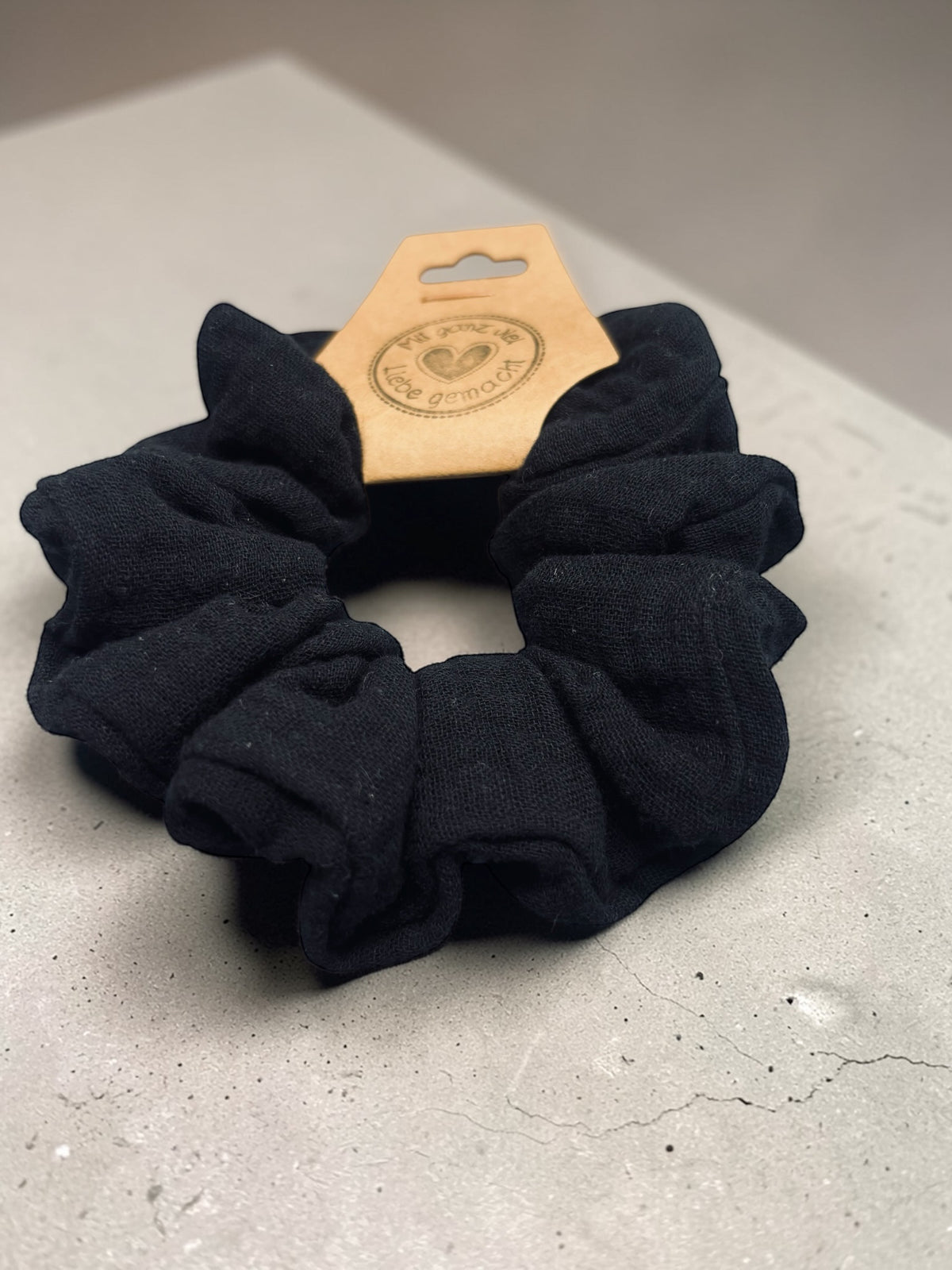 Großer handgemachter schwarzer Musselin-Scrunchie aus schräger Perspektive mit sichtbarer Stoffstruktur
