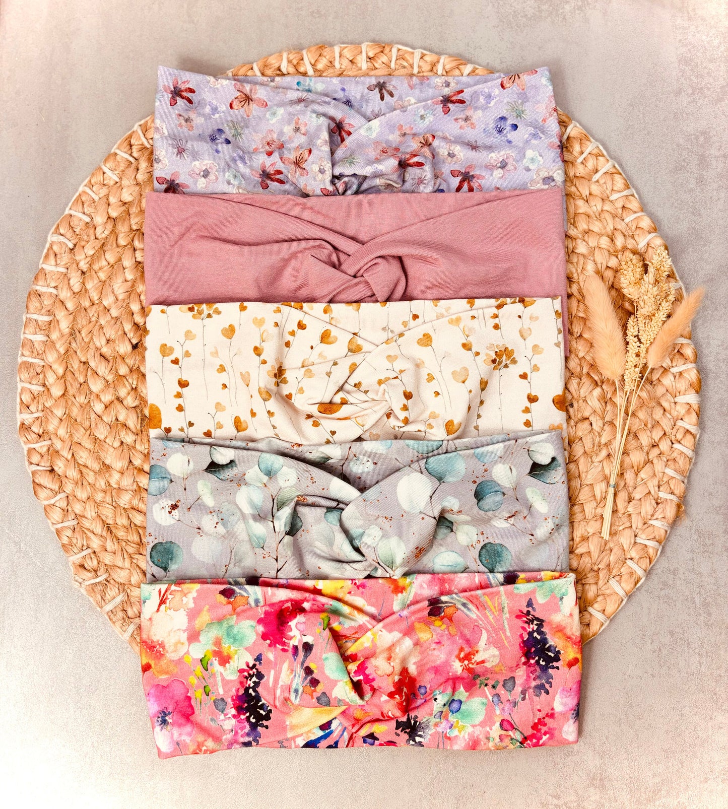 Handgemachtes Twist Stirnband – alle 5 Farben von oben auf schöner Unterlage: Lila mit Blumen, Rosa, Creme mit Herzen, Eukalyptus, Rosa mit Blumen Bunt | OhMamaLina