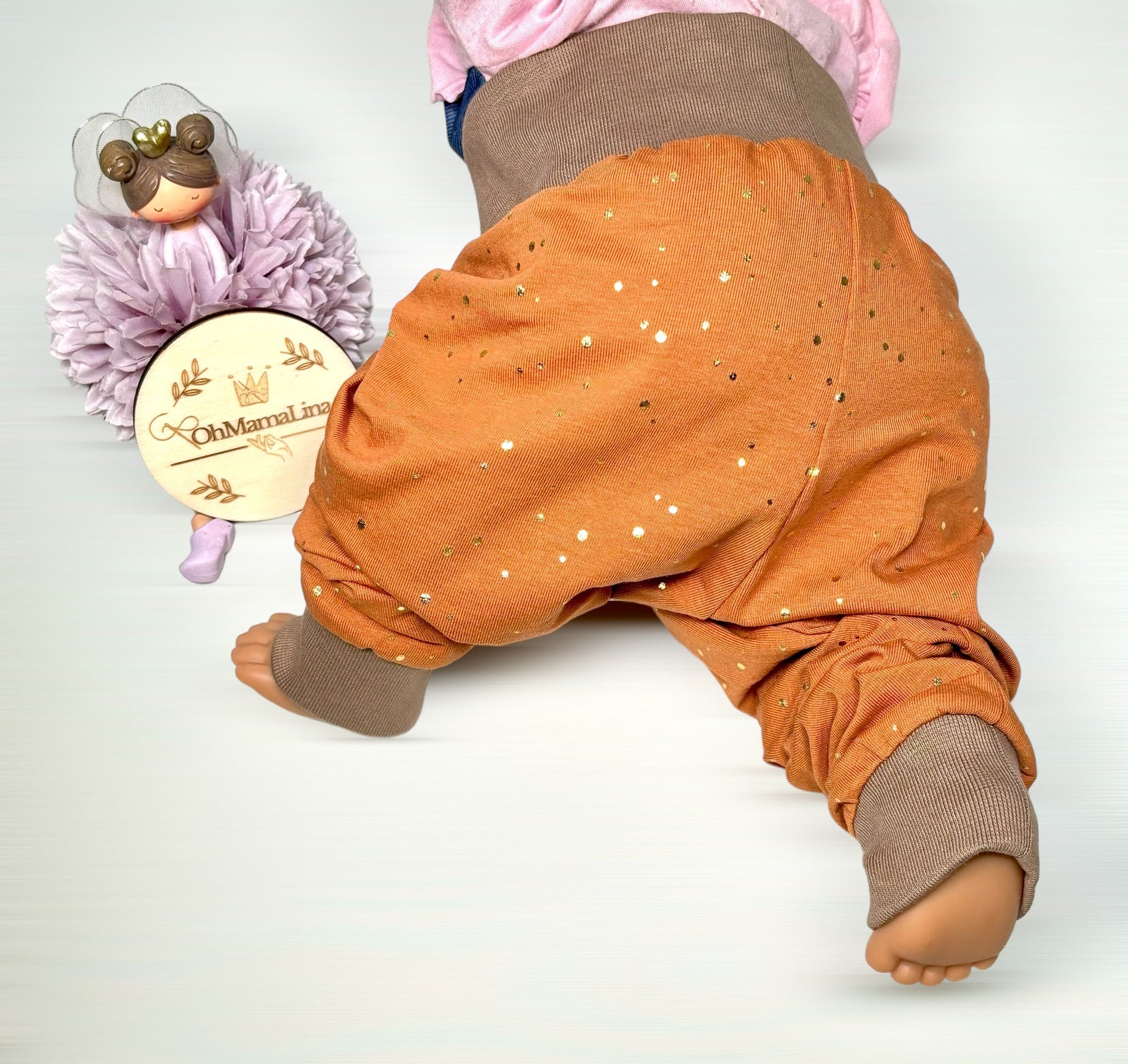Handgemachte Baby Leggings in Rost mit goldenen Folien-Tupfen – Baby liegt, Seitenansicht