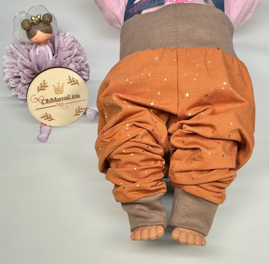 Handgemachte Baby Leggings in Rost mit goldenen Folien-Tupfen und taupefarbenem Bündchen – Vorderansicht an Baby